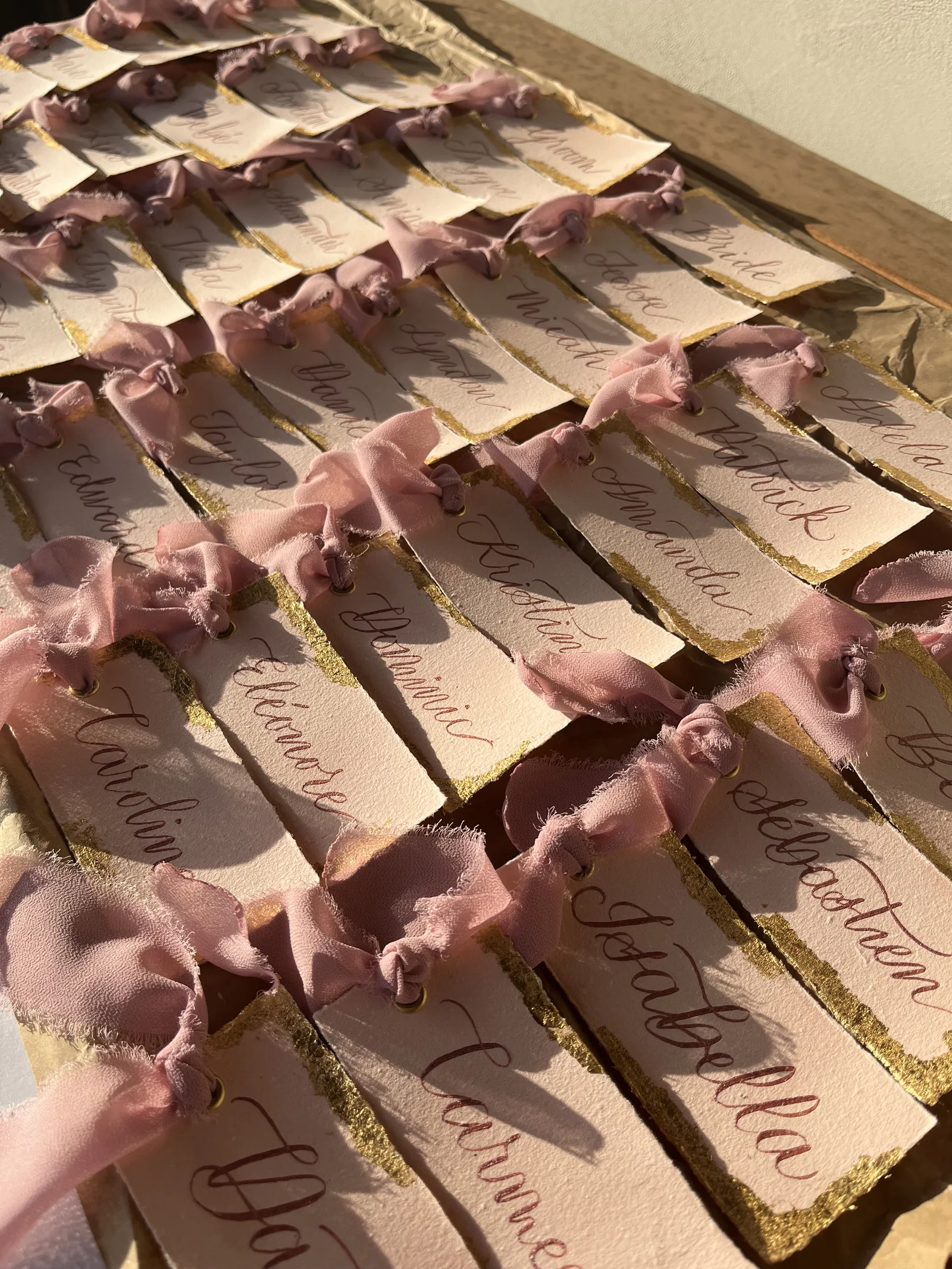Reihen handbeschrifteter Platzkarten mit roséfarbenem Band