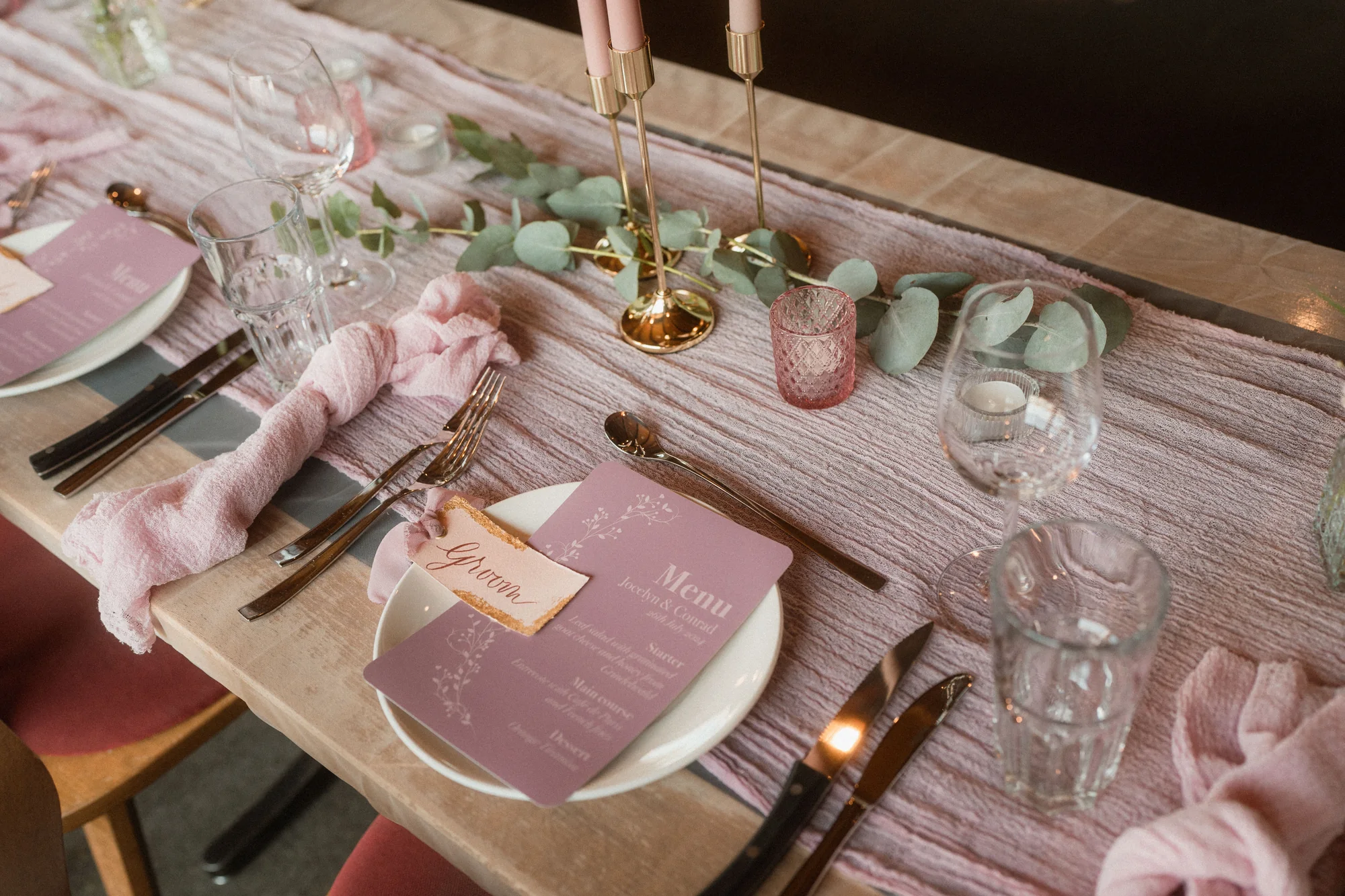 Roséfarbener Hochzeitstisch mit handbeschrifteter Platzkarte und abgestimmten Menüs